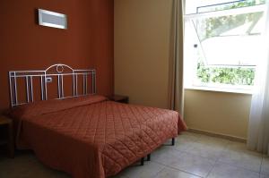 a bedroom with a bed with a red comforter and a window at Hotel San Martino in Cassibile