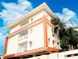 a white building with a palm tree in front of it at Skyla Serviced Apartments in Hyderabad