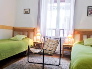 a bedroom with two beds and a chair and a window at Apartment Goélands by Interhome in Biarritz