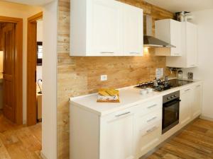 a white kitchen with white cabinets and wooden walls at Apartment Cjase da Maestre-1 by Interhome in Raveo