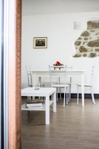 a white dining room table with chairs and a white table at Apartment Casa Rasat-2 by Interhome in Ovasta