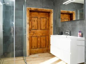 a bathroom with a sink and a wooden door at Apartment Cjase da Maestre-2 by Interhome in Raveo