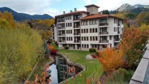 ein großes weißes Gebäude neben einem Fluss in der Unterkunft Комплекс Падалото "ЕТНО" in Smoljan