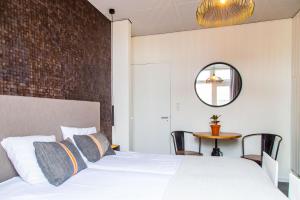 a bedroom with a white bed with a brick wall at Hotel Pannenkoekhuis Vierwegen in Domburg