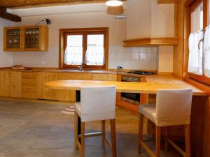 a kitchen with a wooden table and white chairs at Holiday Home Stali di Ettore by Interhome in Ovaro