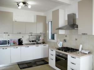 een keuken met witte kasten en een fornuis met oven bij Apartment La Pineta - SLR112 by Interhome in Costarainera