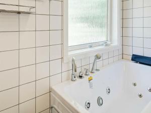 Vester Sømarkenにある4 person holiday home in Aakirkebyの白いバスルーム(バスタブ付)、窓が備わります。