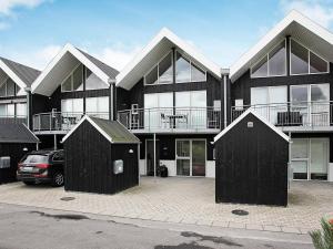 ein großes Gebäude mit zwei Schuppen auf einem Parkplatz in der Unterkunft Three-Bedroom Holiday home in Løkken 22 in Løkken