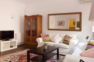 sala de estar con sofá blanco y espejo en Letsgo Camp Nou Apartment, en Barcelona