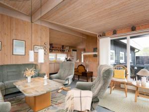 ein Wohnzimmer mit Sofa, Stühlen und einem Tisch in der Unterkunft Seaside Serenity in Blokhus-By Traum in Blokhus
