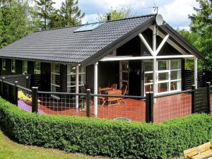 ein Haus mit einem schwarzen Dach und einem Zaun in der Unterkunft 6 person holiday home in Hadsund in Odde