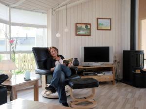 a woman sitting in a chair reading a book at 8 person holiday home in Rude in Rude