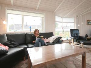 a woman sitting on a couch in a living room at 8 person holiday home in Rude in Rude