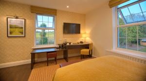 a bedroom with a desk and a tv on the wall at Denbies Vineyard Hotel in Dorking