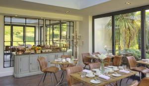 a dining room with tables and chairs and windows at Denbies Vineyard Hotel in Dorking