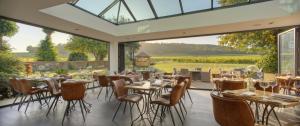 a dining room with tables and chairs and a large window at Denbies Vineyard Hotel in Dorking