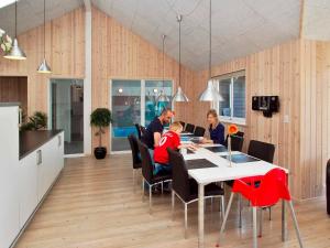 eine Gruppe von Menschen, die an einem Tisch in einer Küche sitzen in der Unterkunft 16 person holiday home in Sydals in Høruphav