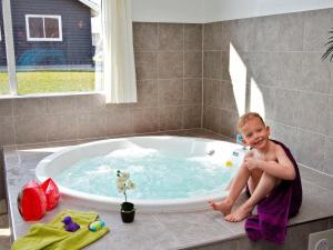 Un ragazzo seduto in una vasca da bagno di 16 person holiday home in Sydals a Høruphav