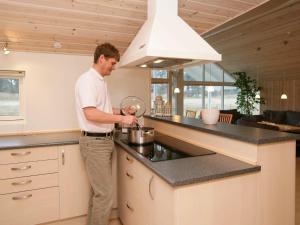 Un homme debout dans une cuisine qui agite un pot dans l'établissement 14 person holiday home in R dby, à Kramnitse