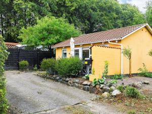 una casa amarilla con una valla al lado de una entrada en 4 person holiday home in Nyk bing M, en Refshammer