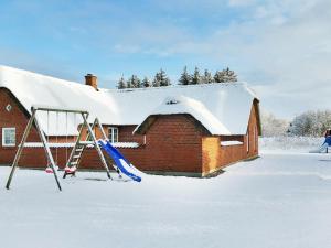 a house with a snow covered roof with a swing at 12 person holiday home in Ulfborg in Husby