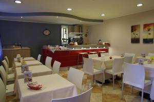 a restaurant with white tables and white chairs and a counter at Hotel San Martino in Cassibile