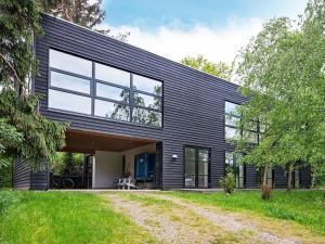 uma casa com revestimento preto e um quintal em Four-Bedroom Holiday home in Ebeltoft 22 em Ebeltoft