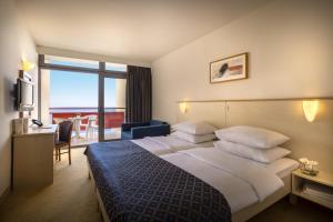 a hotel room with a large bed and a view of the ocean at Rubin Hotel in Poreč