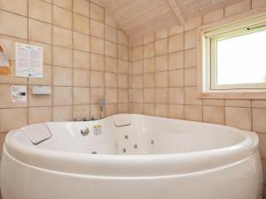 uma banheira branca na casa de banho com uma janela em 8 person holiday home in Idestrup em Bøtø By