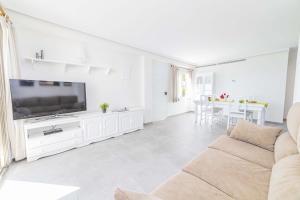 a white living room with a couch and a television at Apartamento Vista Brava in Playa de Muro