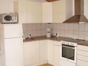 a kitchen with white cabinets and a white refrigerator at 6 person holiday home in R dby in Kramnitse