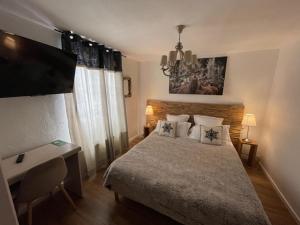 een slaapkamer met een bed, een bureau en een televisie bij Hotel Le Blanche Neige in Valberg