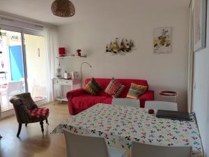a living room with a table and a red couch at Appartement Pour 4 Personnes Avec Vue Sur Le Port De Plaisance- Residence Le Genois in Capbreton