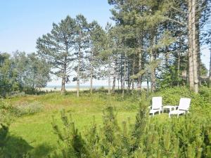 two white chairs sitting in a field with trees at 5 person holiday home in R m in Rømø Kirkeby