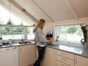 a woman standing in a kitchen preparing food at Three-Bedroom Holiday home in Væggerløse 11 in Marielyst