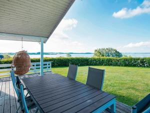 Egernsundにある6 person holiday home in Egernsundの木製テーブルと椅子付きのデッキから水辺の景色を望めます。