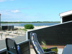 ein Paar Stühle auf einer Veranda neben einem Strand in der Unterkunft 6 person holiday home in Juelsminde in Juelsminde