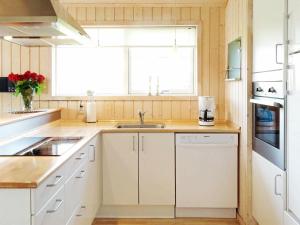 eine Küche mit weißen Schränken, einem Waschbecken und einem Fenster in der Unterkunft 6 person holiday home in Tranek r in Tranekær
