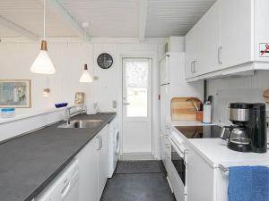 Strandbyにある4 person holiday home in Strandbyの白いキャビネットとシンク付きのキッチン