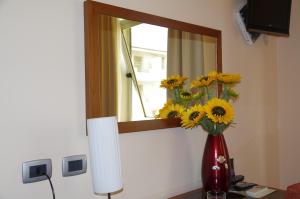 a vase of sunflowers in front of a mirror at Hotel San Martino in Cassibile
