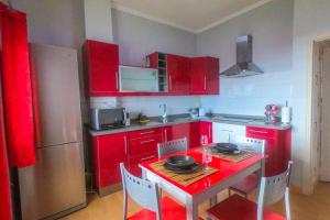 eine Küche mit roten Schränken, einem roten Tisch und Stühlen in der Unterkunft Casa Toribio in El Río