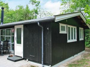 a black house with a white door and a porch at 6 person holiday home in Str by in Strøby
