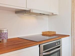 La cuisine est équipée de placards blancs et d'un four avec plaques de cuisson. dans l'établissement 4 person holiday home in Gudhjem, à Gudhjem
