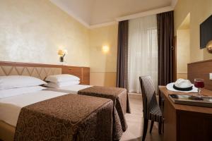 a hotel room with two beds and a desk at Hotel Kennedy in Rome