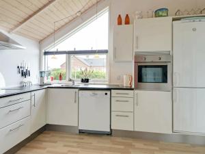 a kitchen with white cabinets and a large window at 6 person holiday home in Tarm in Hemmet