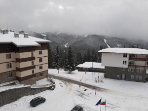 a snow covered parking lot in front of a building at Pamporovo Rhodopi Pearl Apartments - Private Apartments in Pamporovo +1 photo