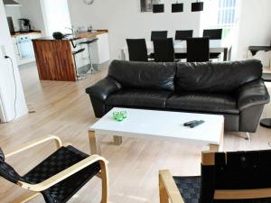 a living room with a black leather couch and a white coffee table at 8 person holiday home in R m in Sønderby
