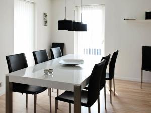 a dining room with a white table and black chairs at 8 person holiday home in R m in Sønderby