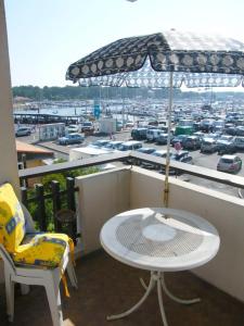 balcón con sombrilla, mesa y sillas en Appartement Pour 3 Personnes Sur Le Port -Residence Cap Sud en Capbreton