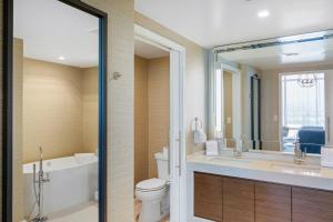 a bathroom with a toilet and a tub and a sink at Omni Frisco at The Star in Frisco
